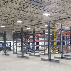 Structural cantilever racking system assembly and floor anchoring in a large industrial warehouse.